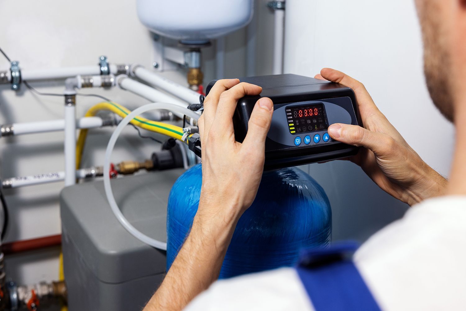 Person using a touchscreen device to monitor a blue industrial tank with attached hoses and valves Person using a touchscreen device to monitor a blue industrial tank with attached hoses and valves