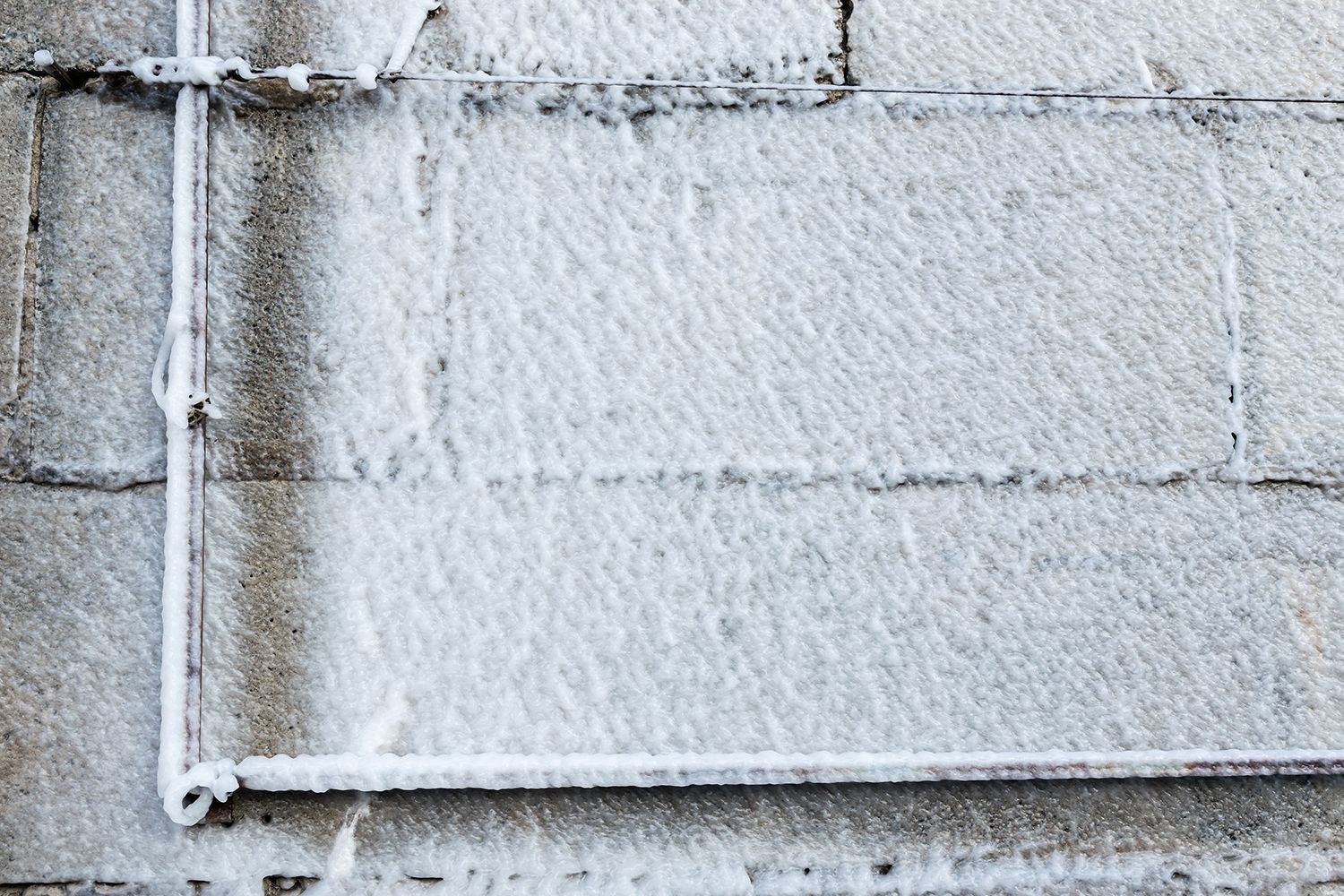 White wall with exposed metal pipes and a horizontal cable or conduit line