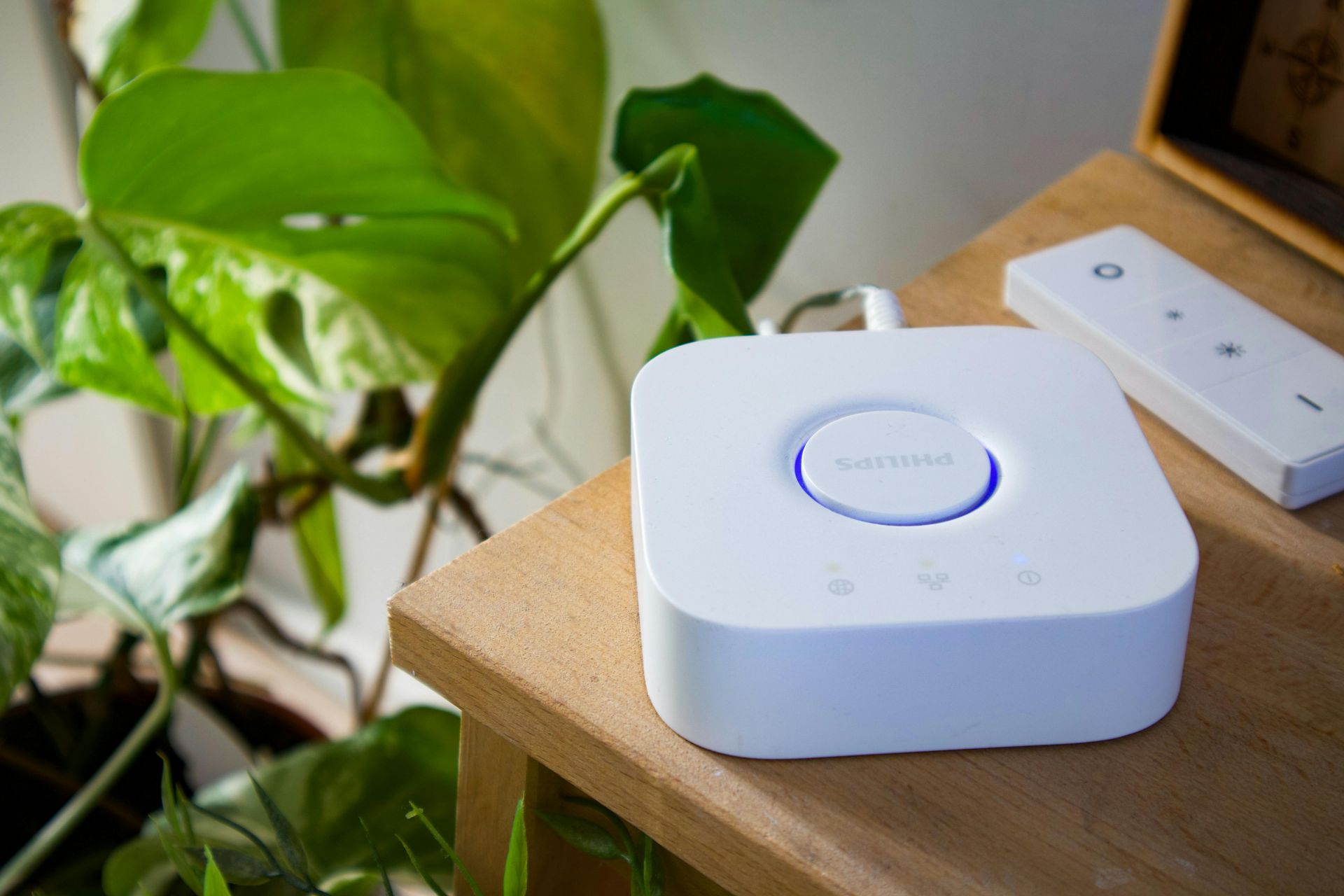 A small white Smart Hub device on a nightstand with a remote beside it.