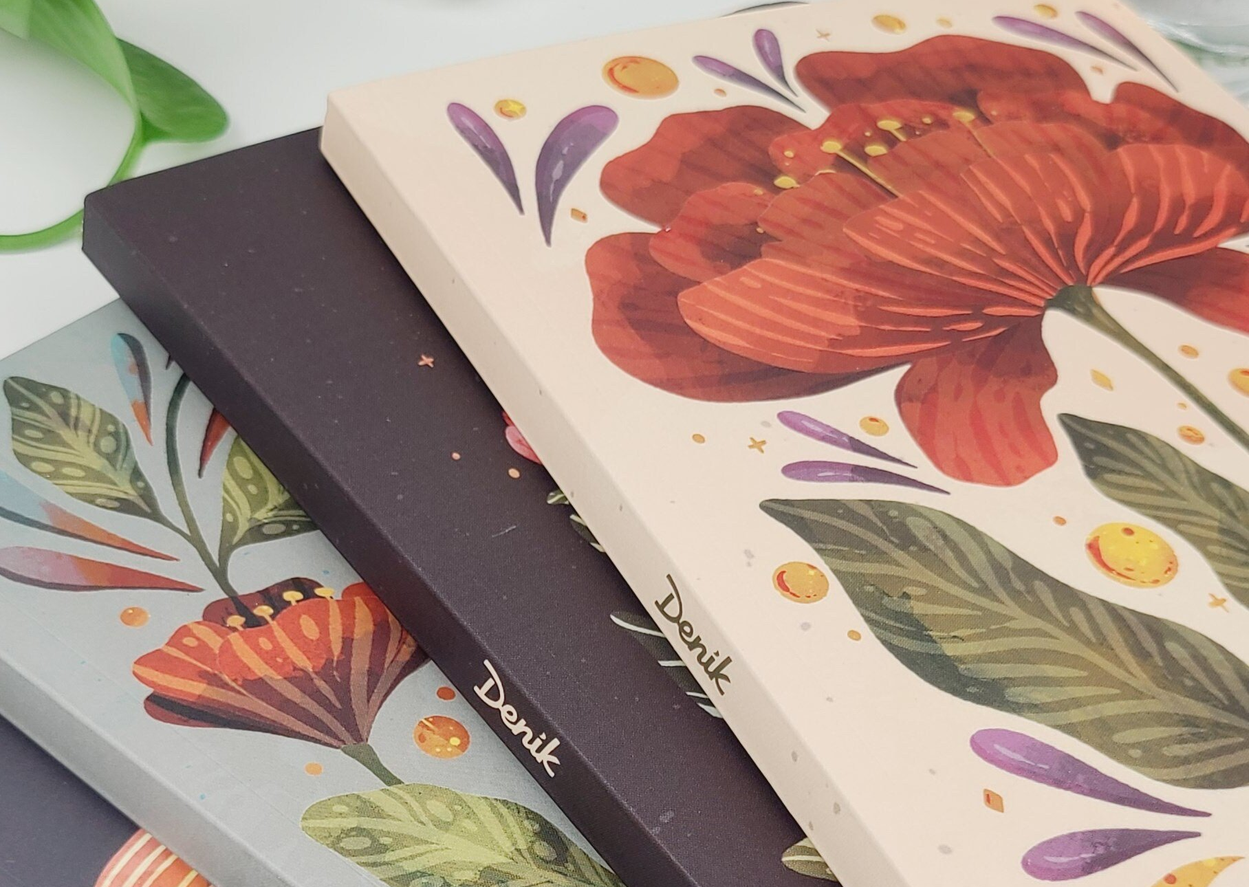 three notebooks with flowers on them are stacked on top of each other
