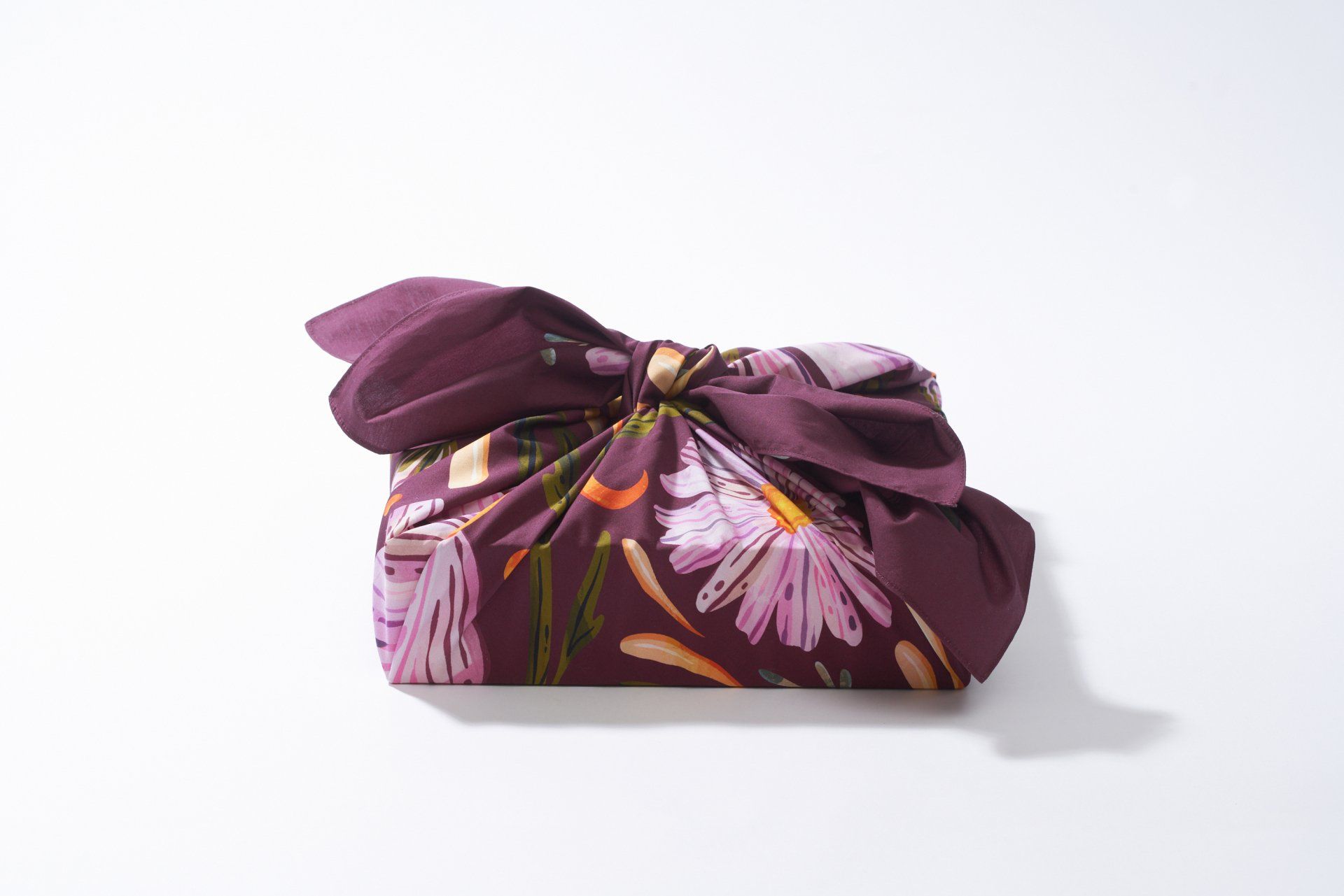 a purple scarf with flowers on it is wrapped in a bow .