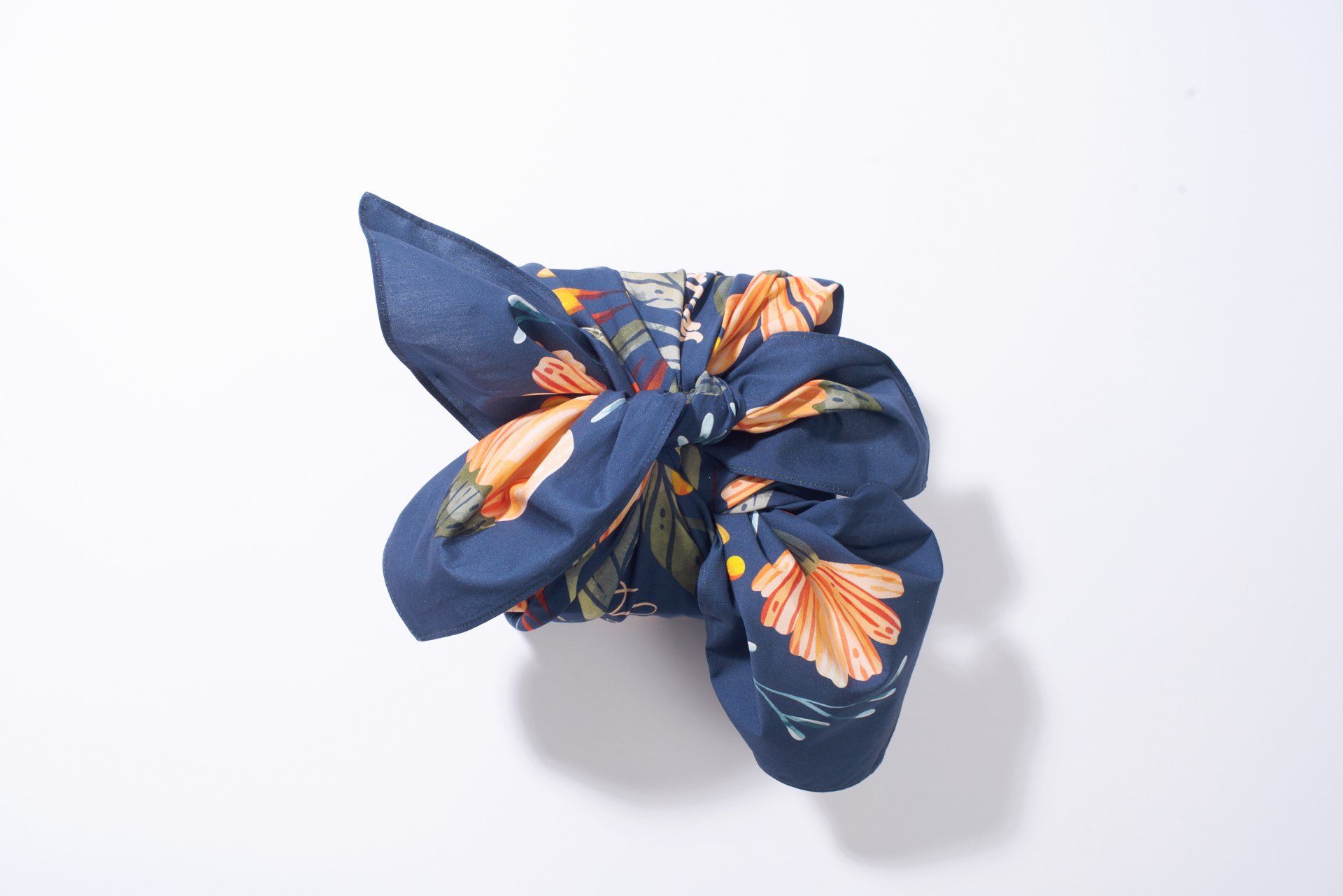 a blue scarf with flowers on it is sitting on a white surface .