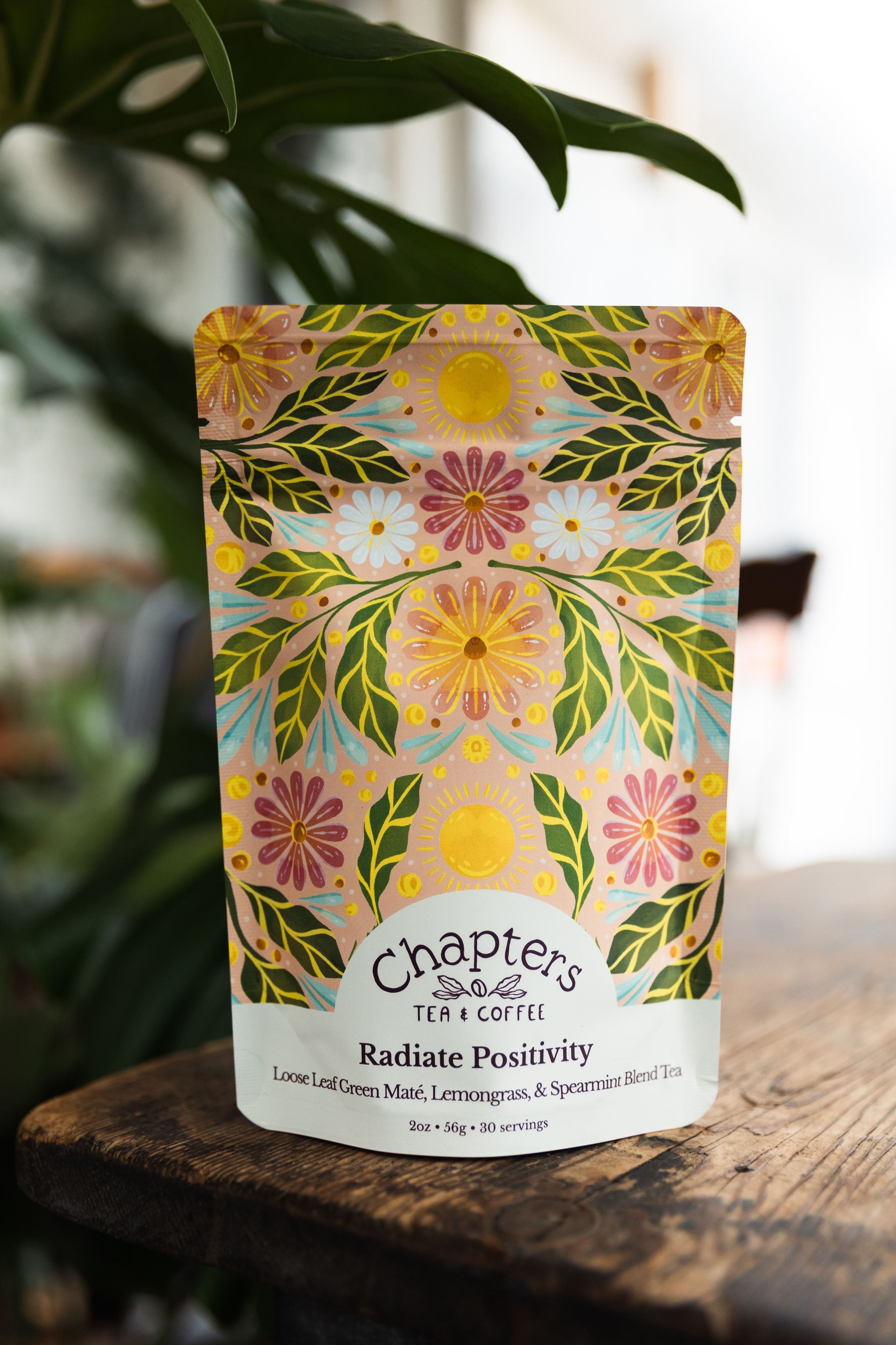 A bag of chapters tea is sitting on a wooden table next to a plant.
