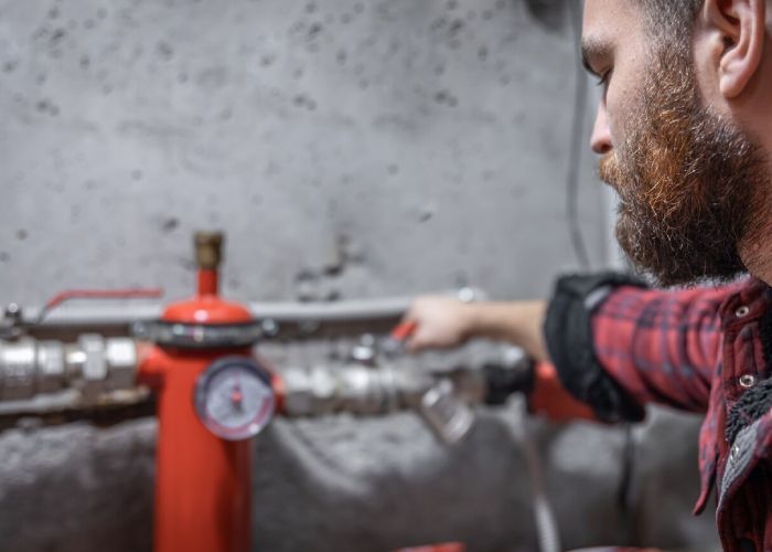 A man with a beard is working on a pipe.
