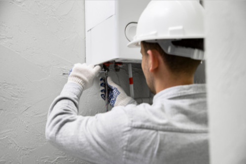 Man repairing water heater during service visit, The Plumbinator Plumbing Co performing repair.