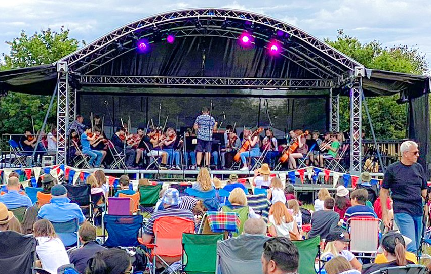 Arc roof stage with an orchestra playing and an audience watching