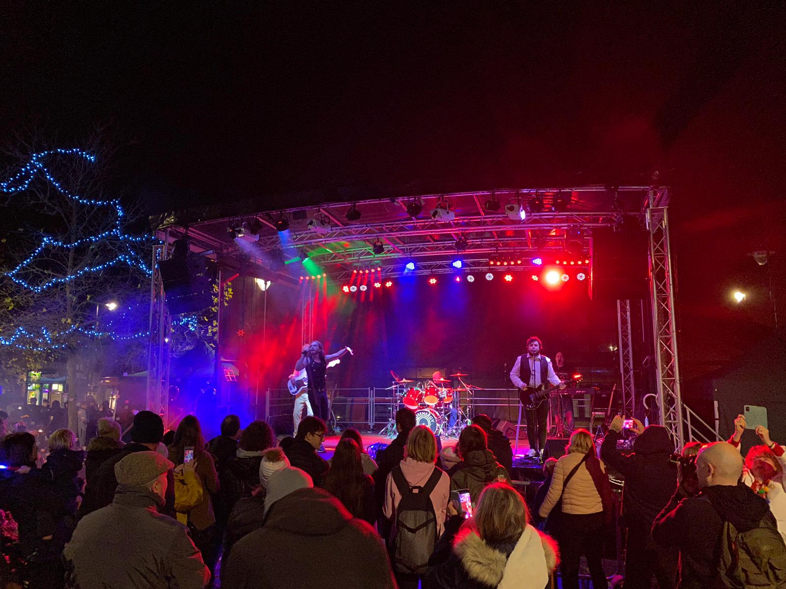 Nighttime shot of the stage with red and blue lighting, a band playing and a crowd