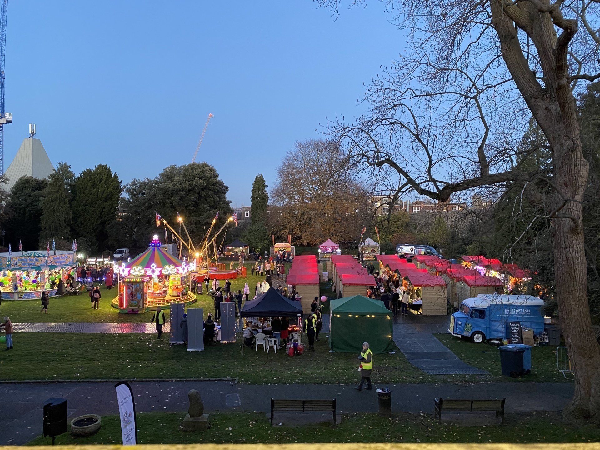 Wide shot of the christmas market event, with wooden chalets and funfair rides