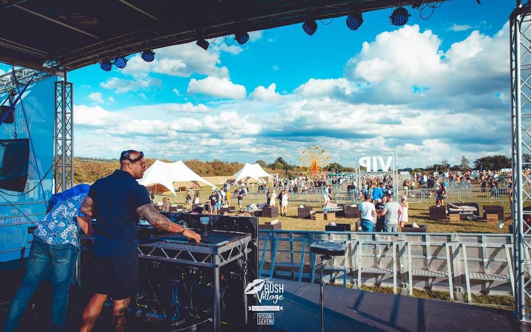 Interior view of the trailer stage set up at an outdoor event with a DJ on the stage and audience