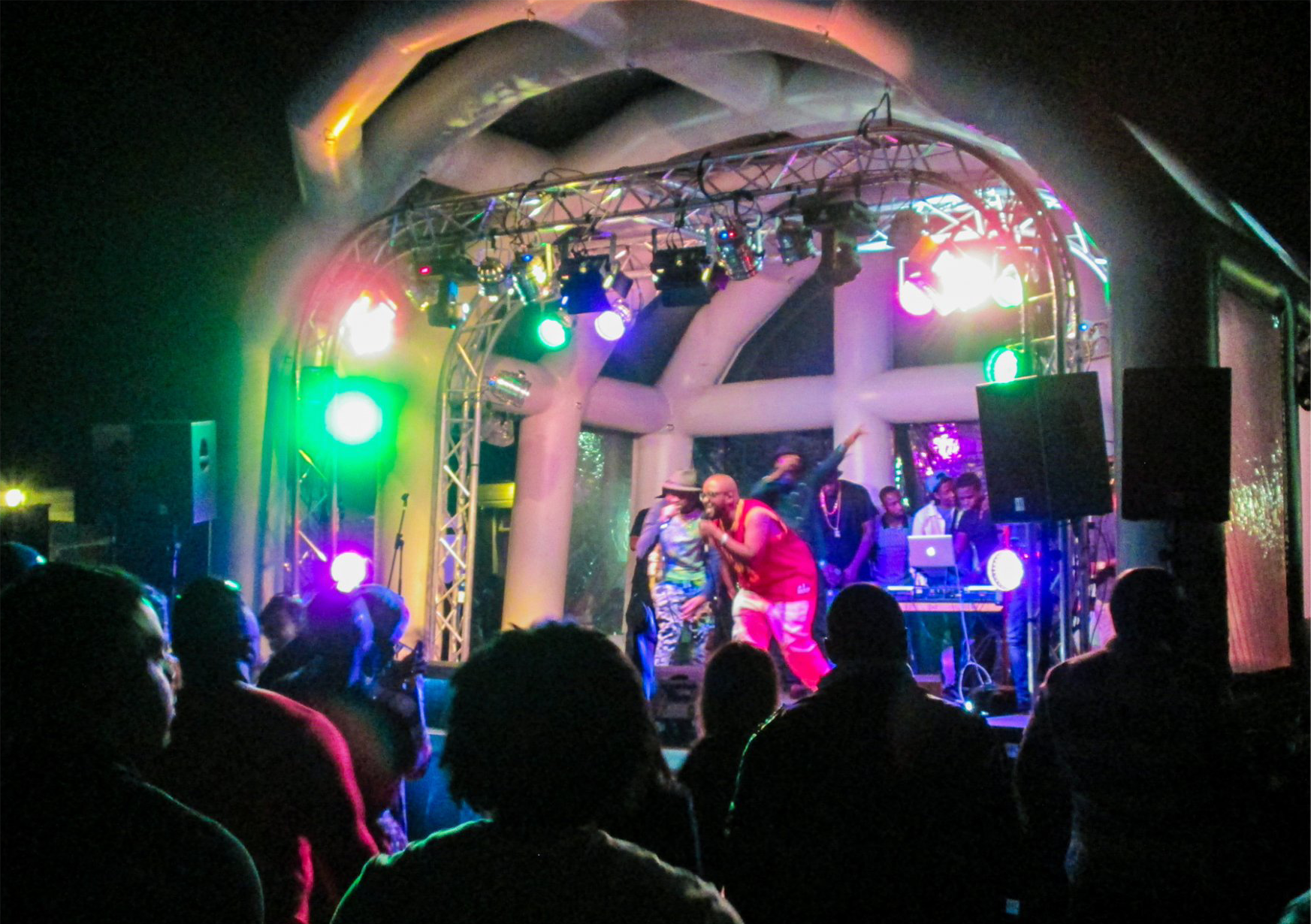 Inflatable roof stage set up for an outdoor event at nighttime with lighting and a band