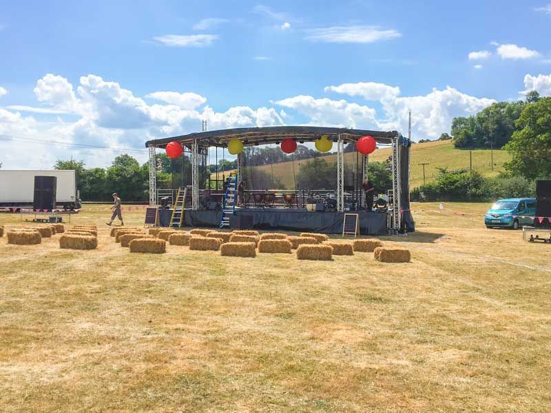 A large trailer stage in a field, with brown grass and blue sky