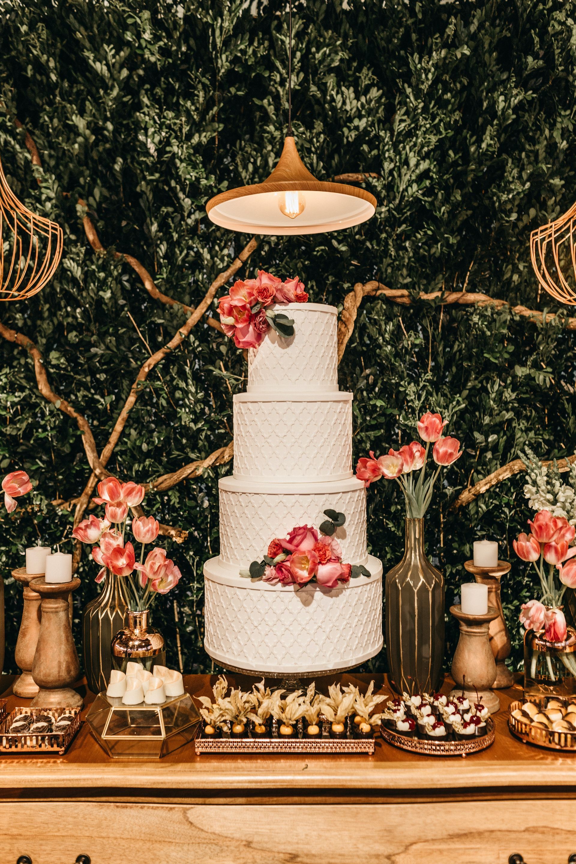 A four tier wedding cake with candles surrounding it.