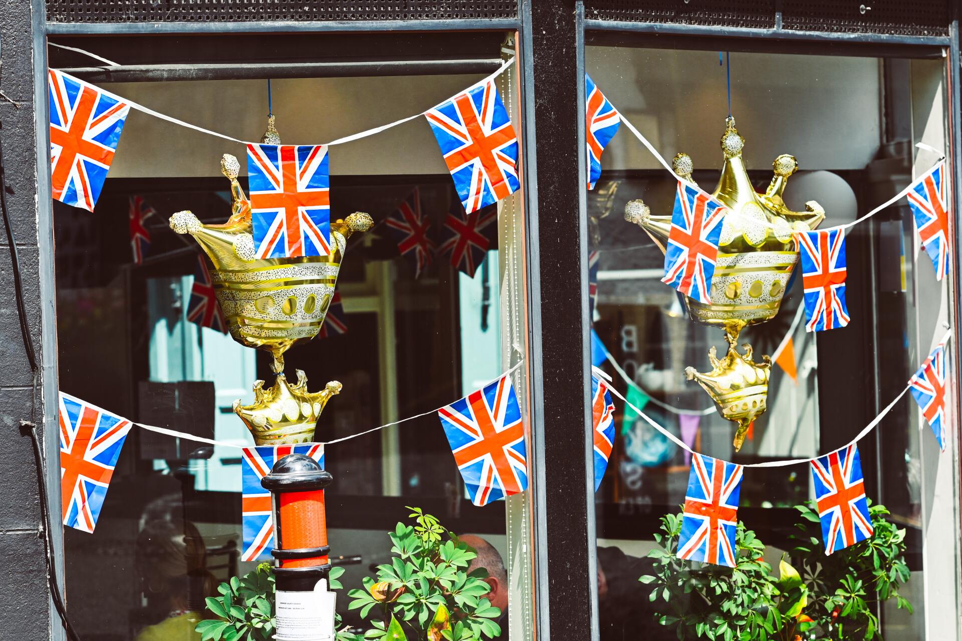 A Shop window with flags hanging in front of inflatable crown decorations