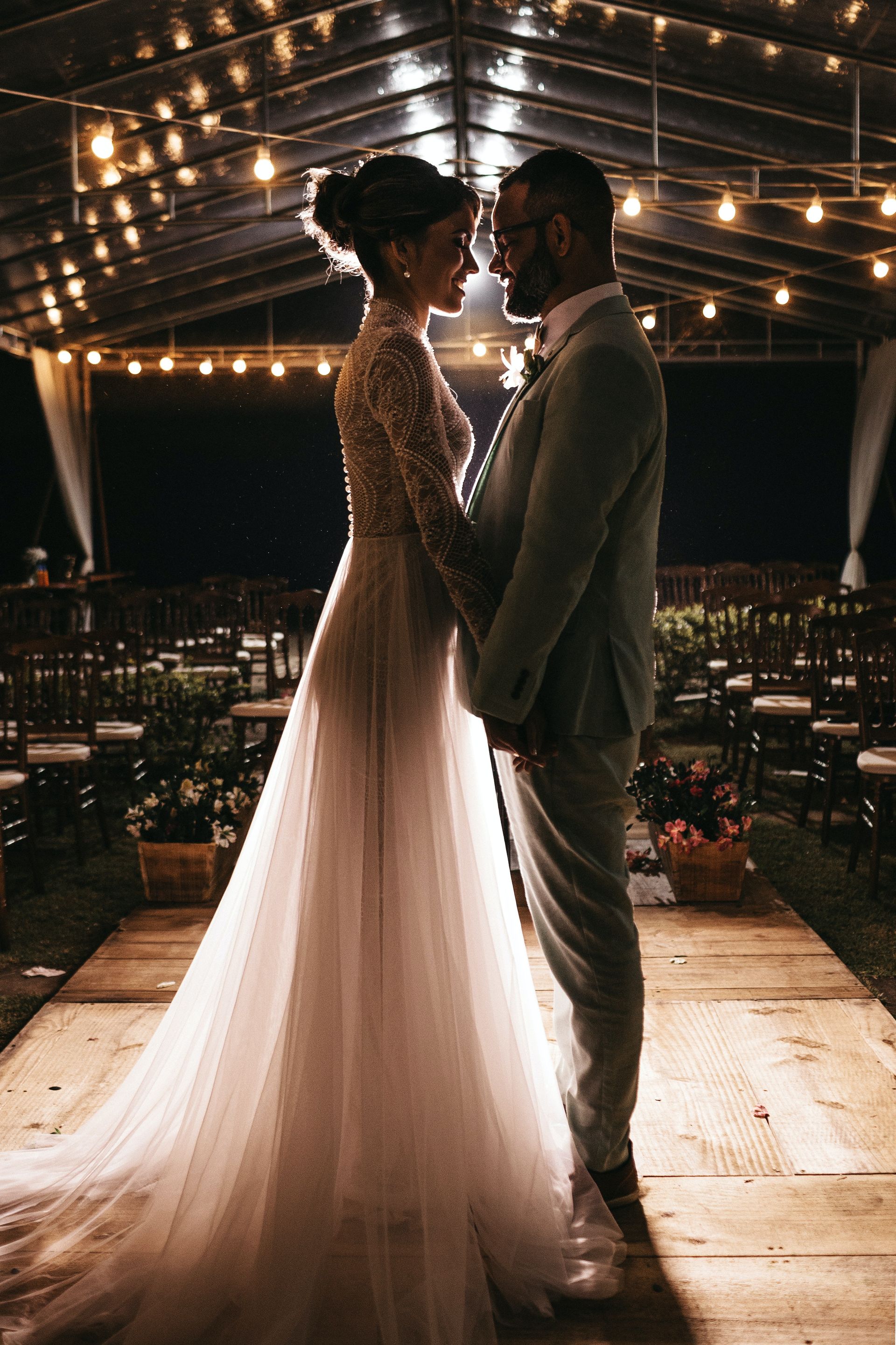 A bride and groom kissing in a barn with fairy lights as a backdrop