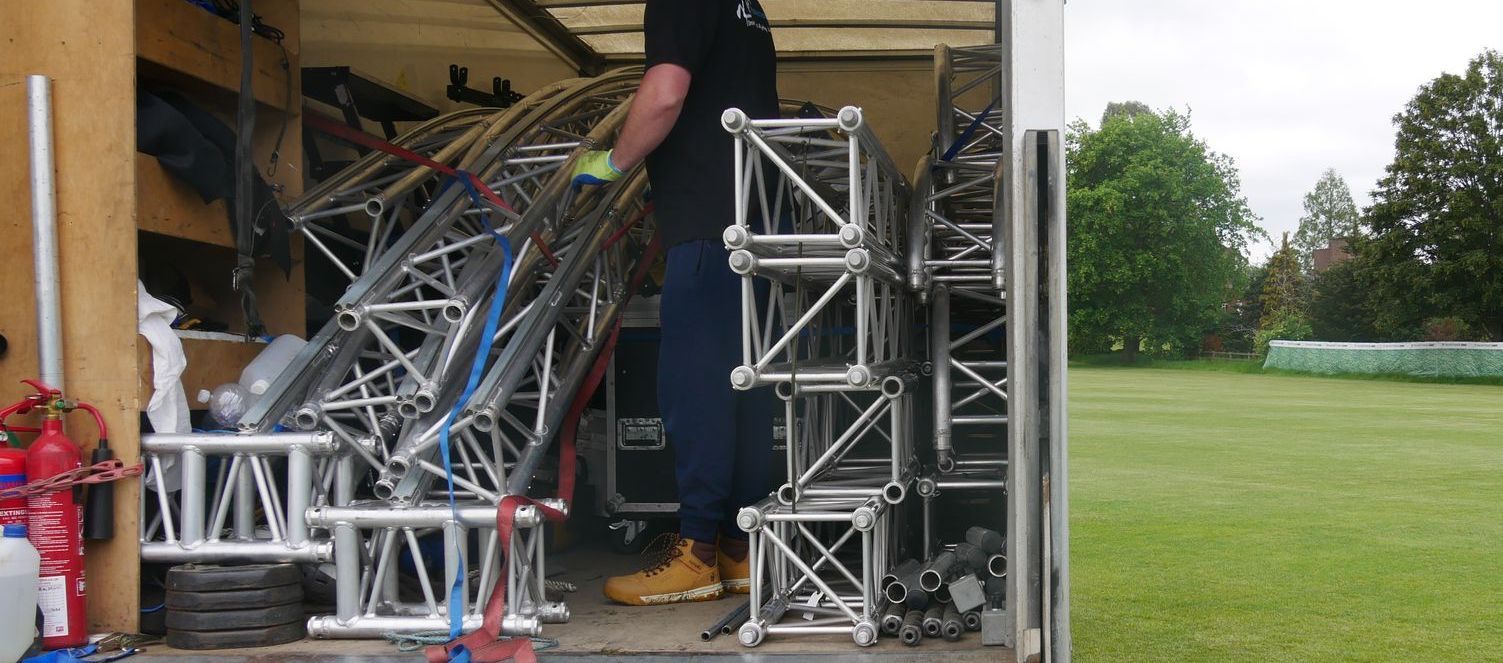 View of the inside of a loaded truck with stage equipment and a crew member handling them