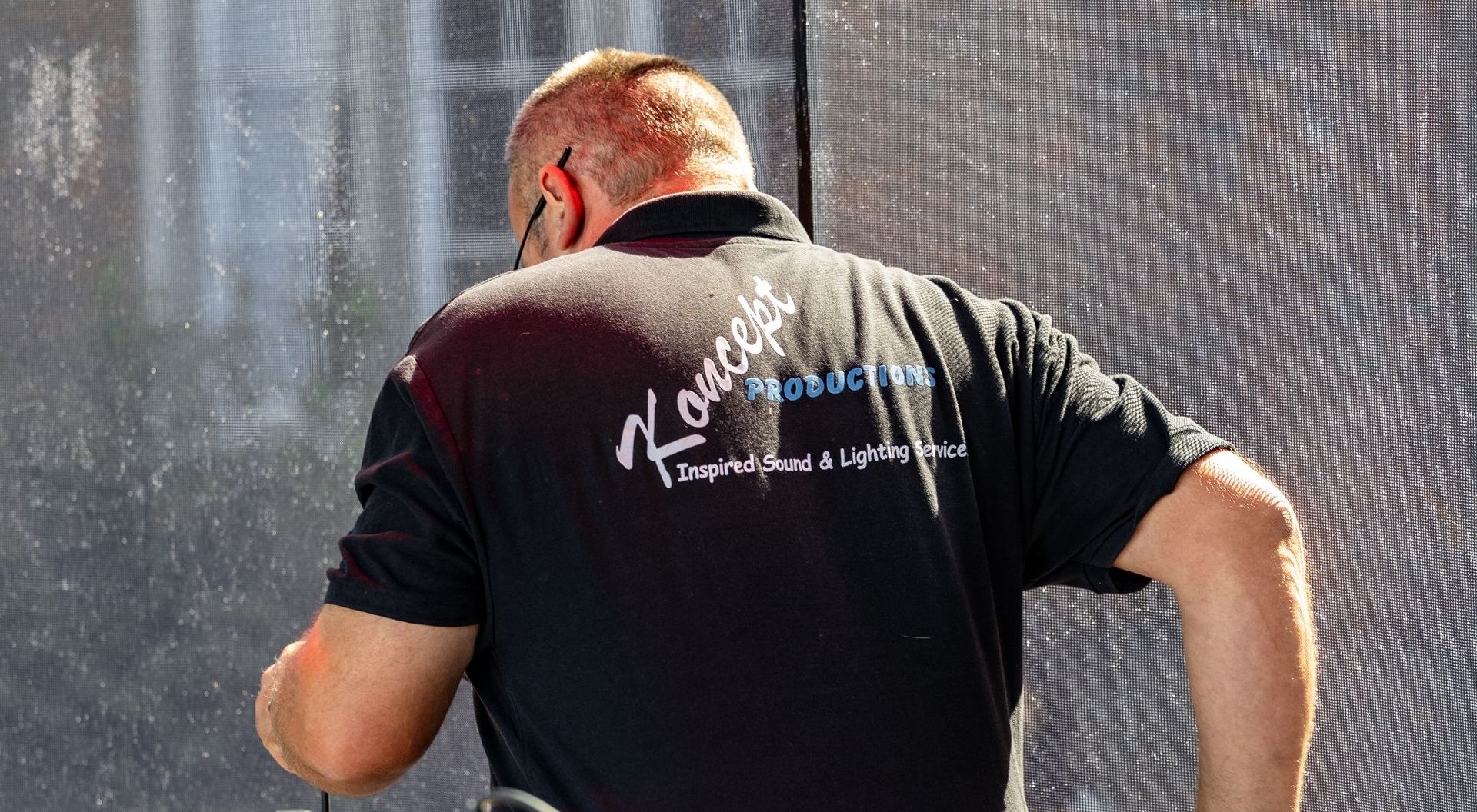 close up of the koncept logo on the back of a crew member's shirt