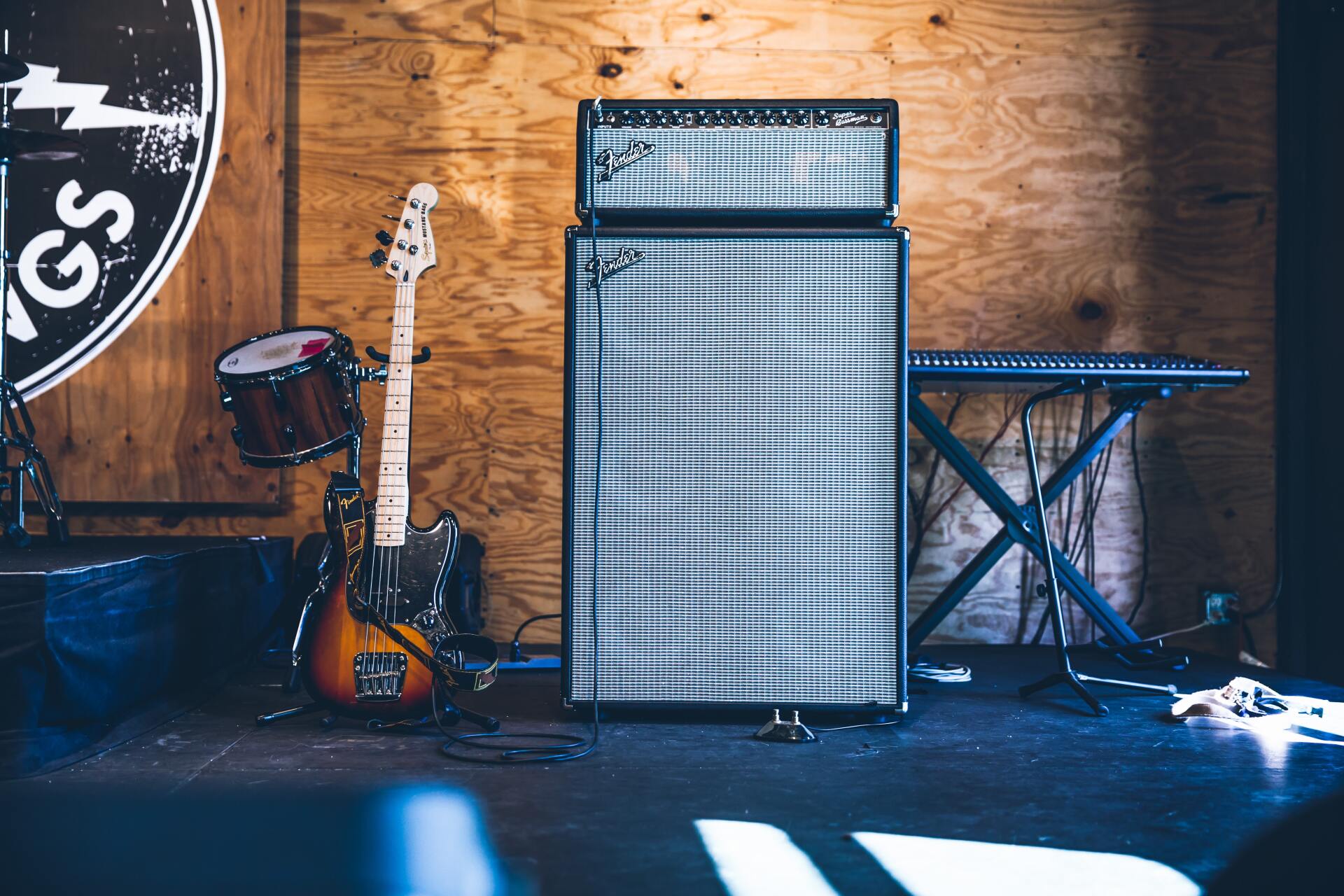 A photo of a large speaker amp with an orange/brown electric guitar next to it. They are in front of a trendy brick wall.