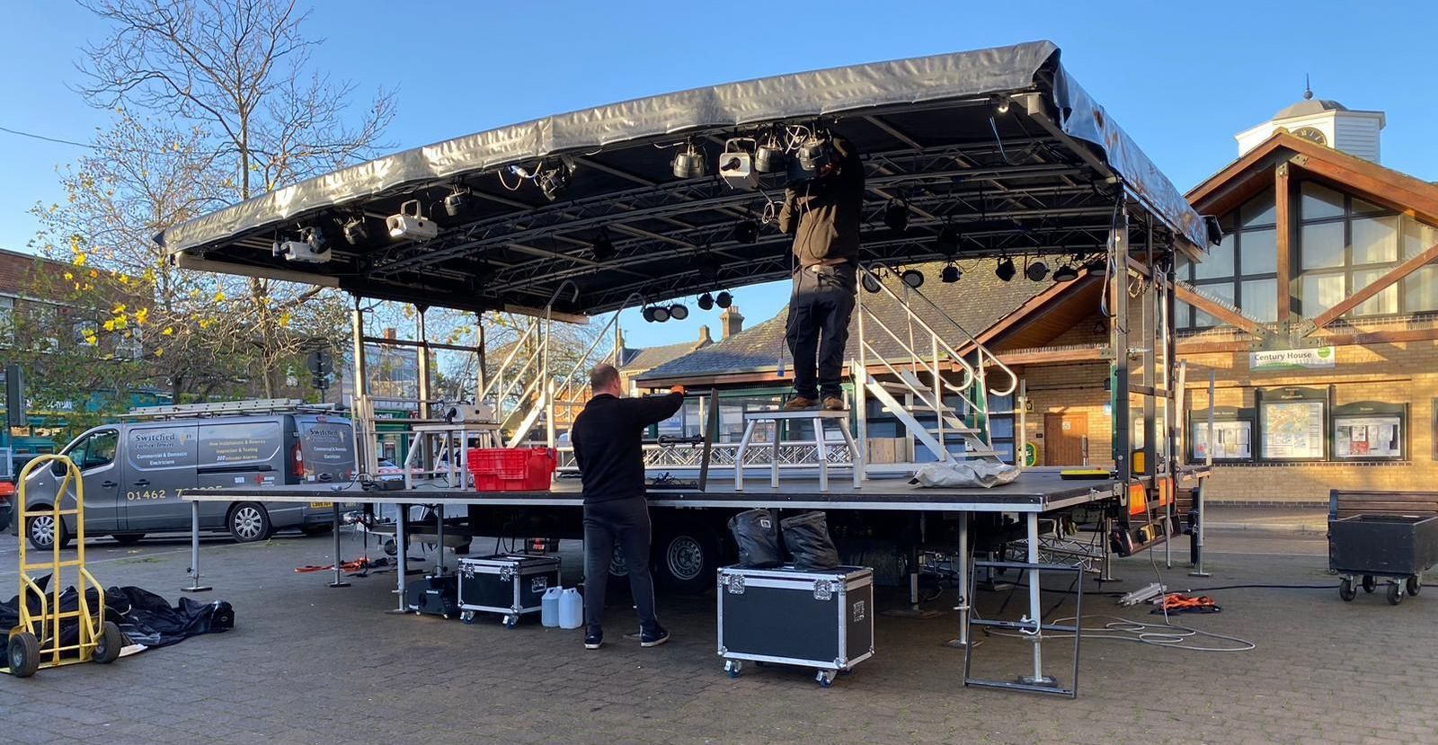 The trailer stage half lifted being set up by two crew members.