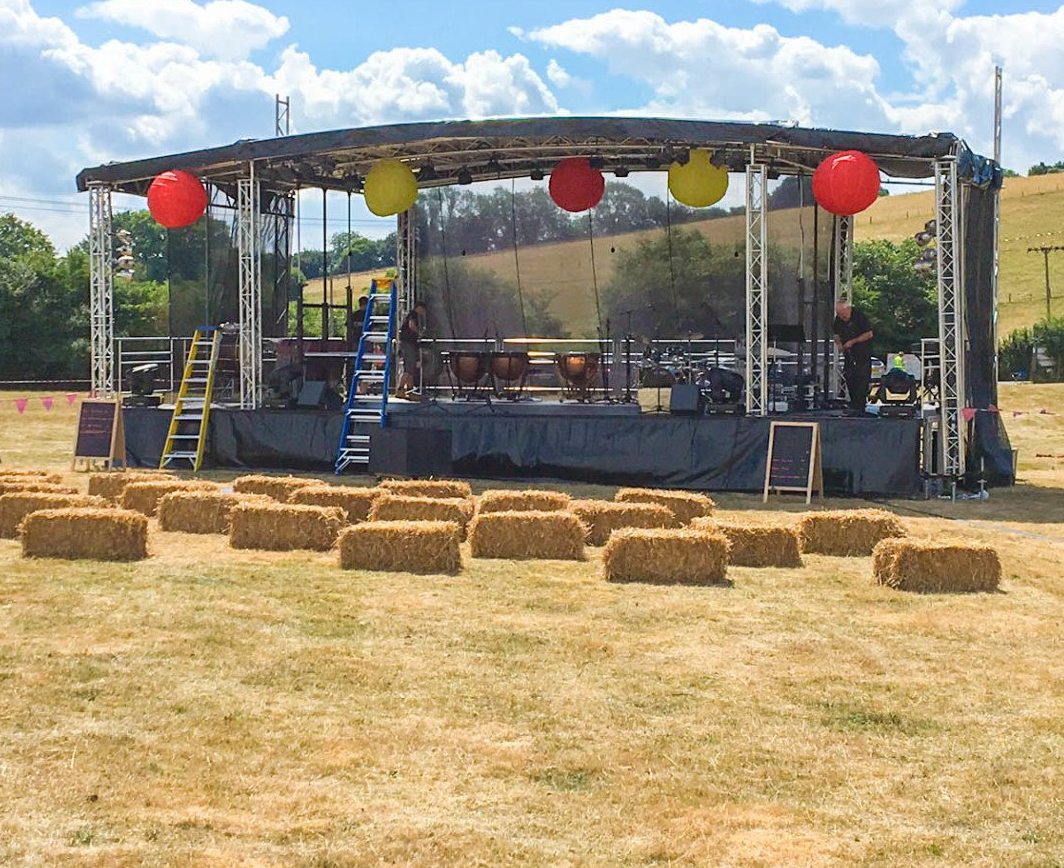 Festival stage set up with in a field with paper lanterns and hay bails