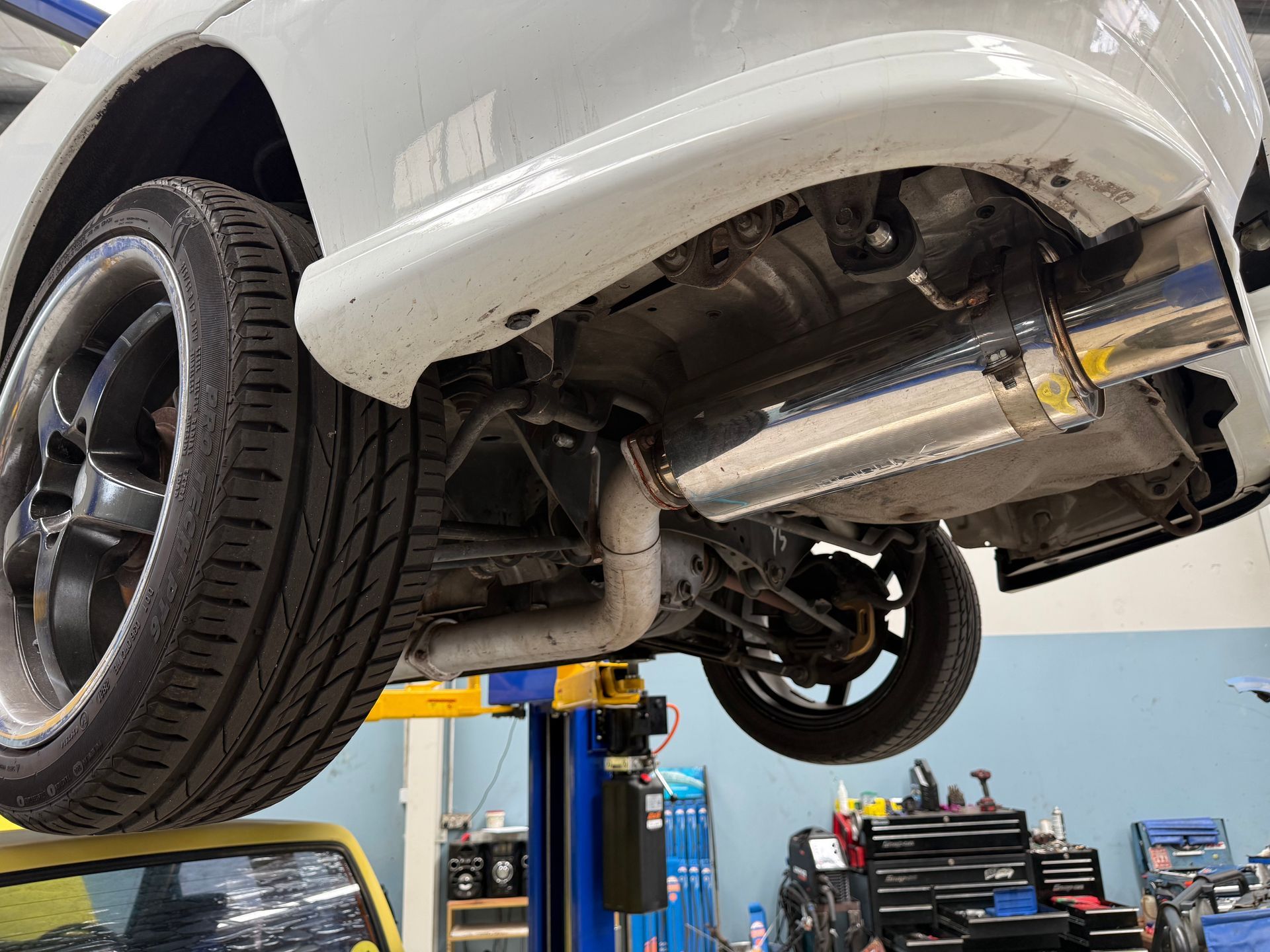 A Car Raised on a Hydraulic Lift in a Garage, Showcasing Its Rear Underside — Mad Monkeys Mechanical in Cairns City, QLD