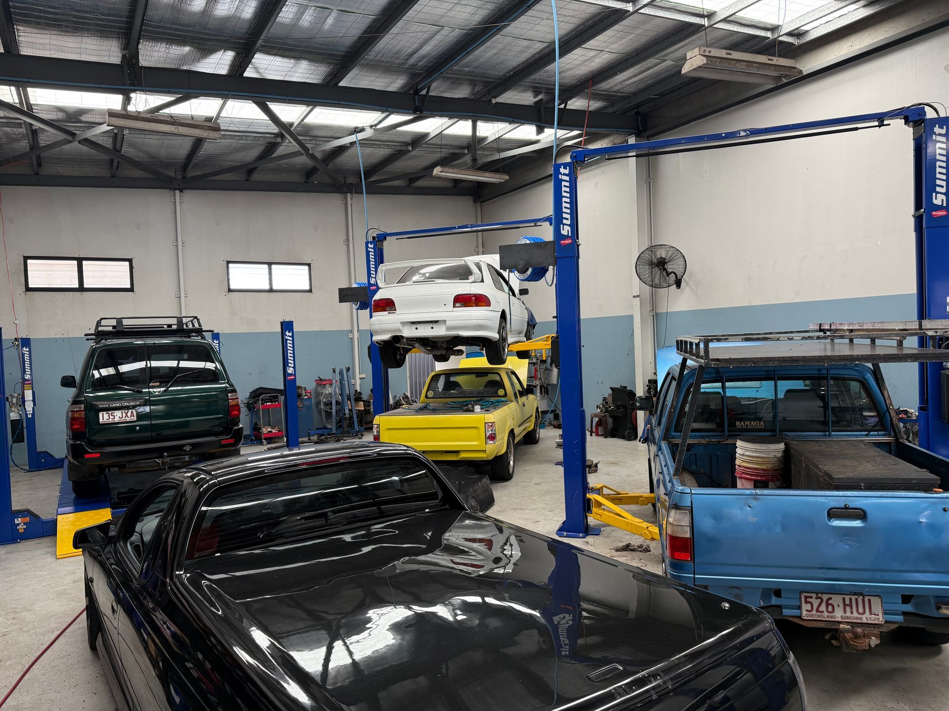 A Vehicle Repair Shop With a Dark Suv, a Yellow Ute, a Blue Pickup Truck — Mad Monkeys Mechanical in Cairns City, QLD
