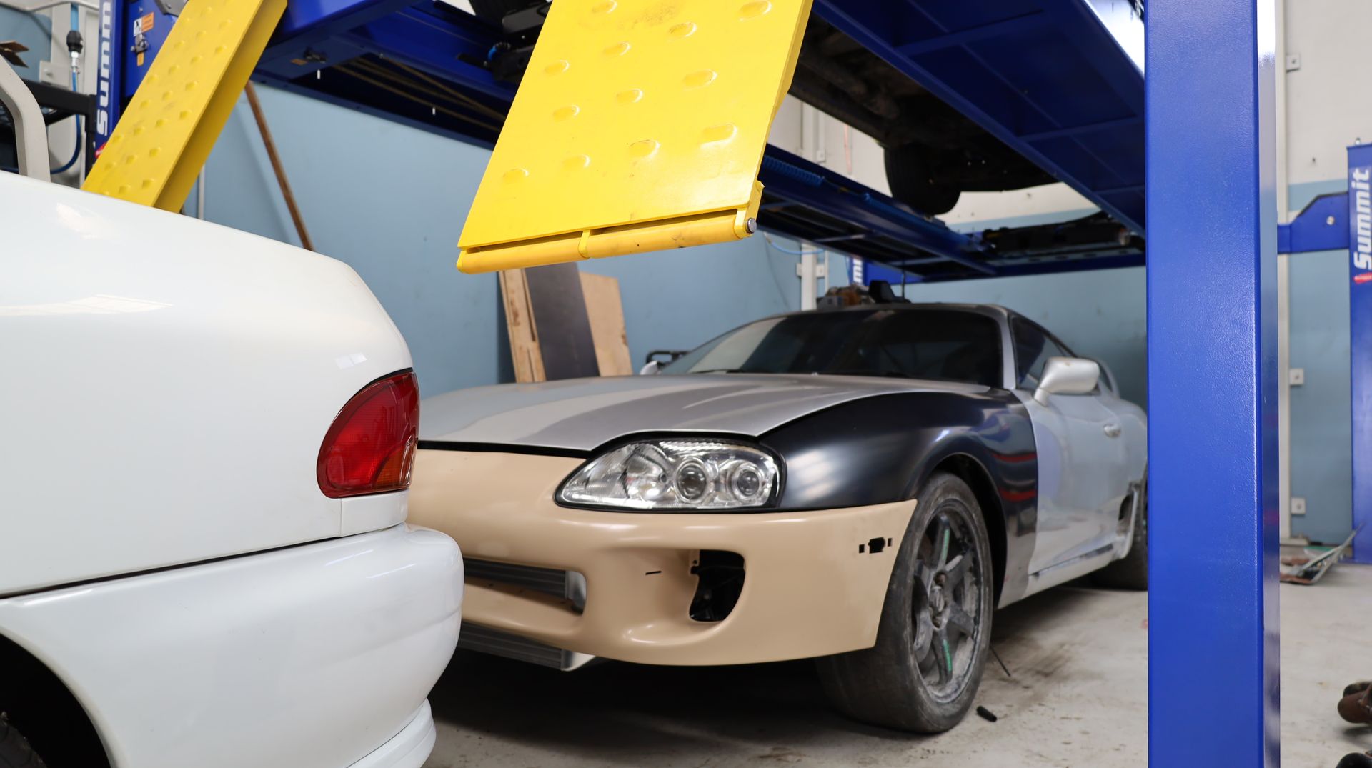 Beige and Black Car Parked in an Auto Shop Beside a White Car and Blue Lift Structure — Mad Monkeys Mechanical in Cairns City, QLD