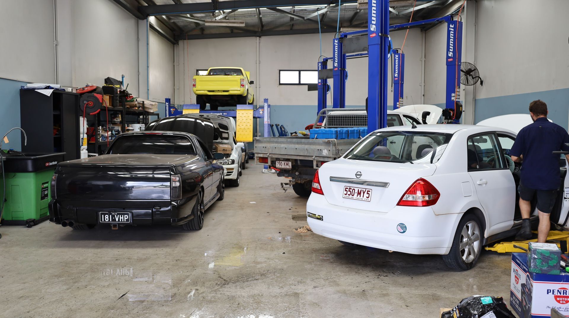 Auto Repair Shop with Two Cars on Lifts and a Mechanic Working Beside a White Car — Mad Monkeys Mechanical in Cairns City, QLD