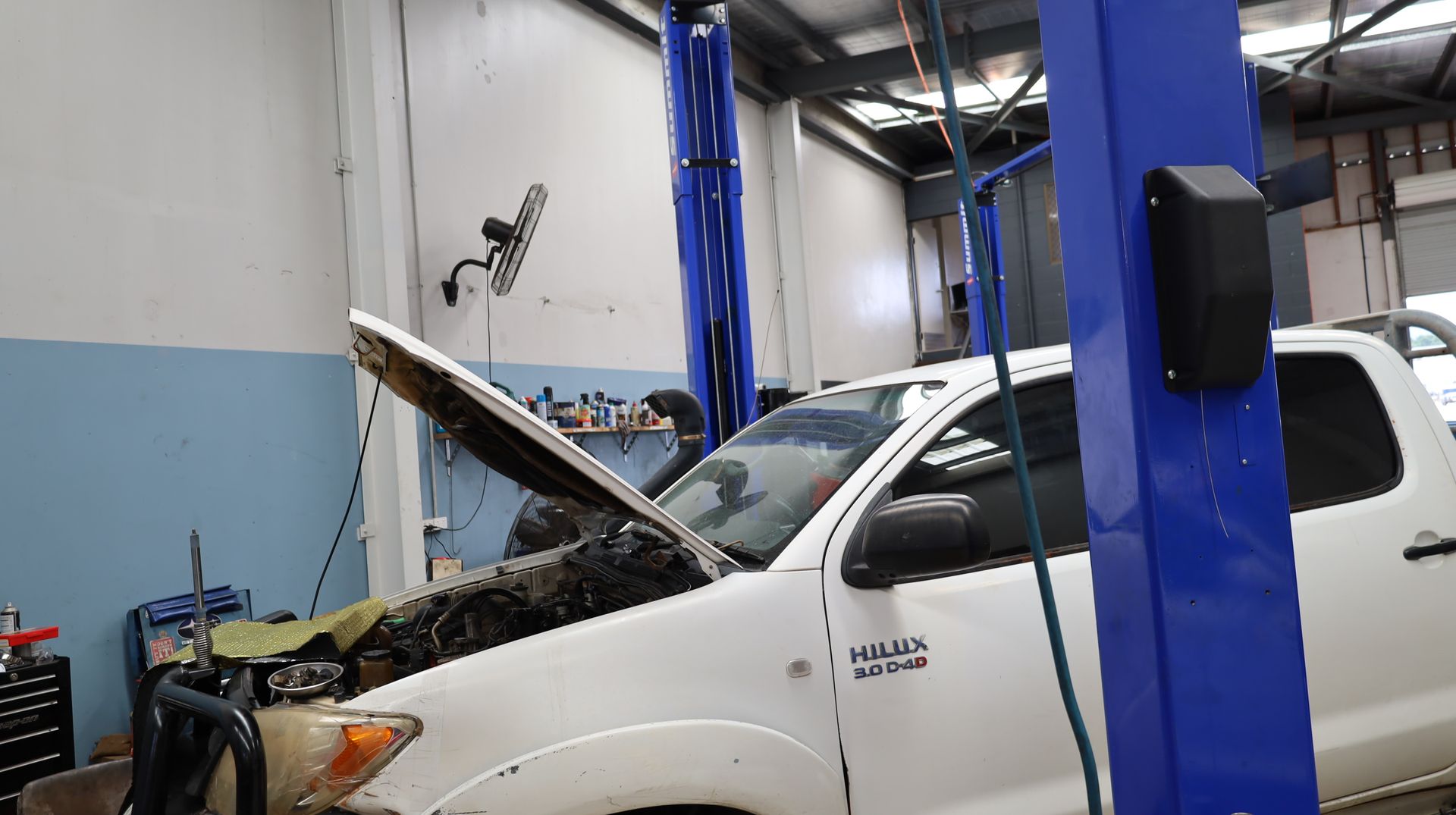 White Pickup Truck with Hood Open in an Auto Repair Shop Next to a Blue Lift — Mad Monkeys Mechanical in Cairns City, QLD