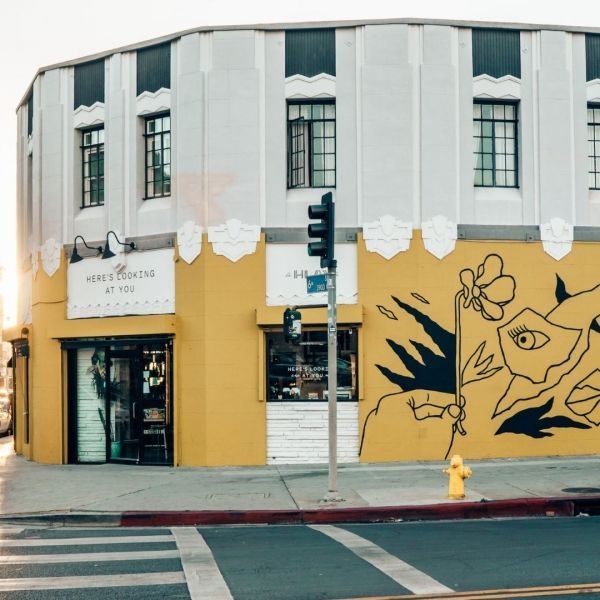 Yellow and white art deco building with mural on corner.