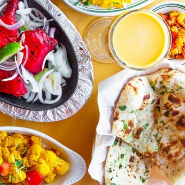 Indian food spread: tandoori chicken, naan, cauliflower, sauce, onions, and lime.