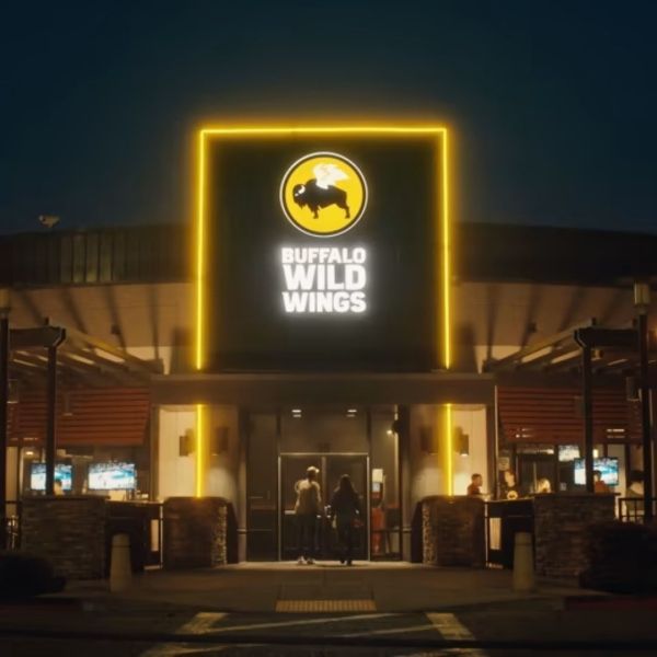 Buffalo Wild Wings restaurant exterior at night with illuminated sign and patrons entering.