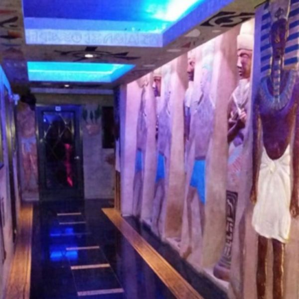 Hallway with Egyptian statues, blue lighting, and a reflective floor.