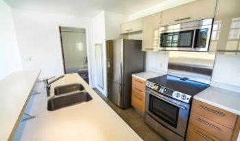 Modern kitchen with stainless steel appliances, light countertops and wood cabinets.