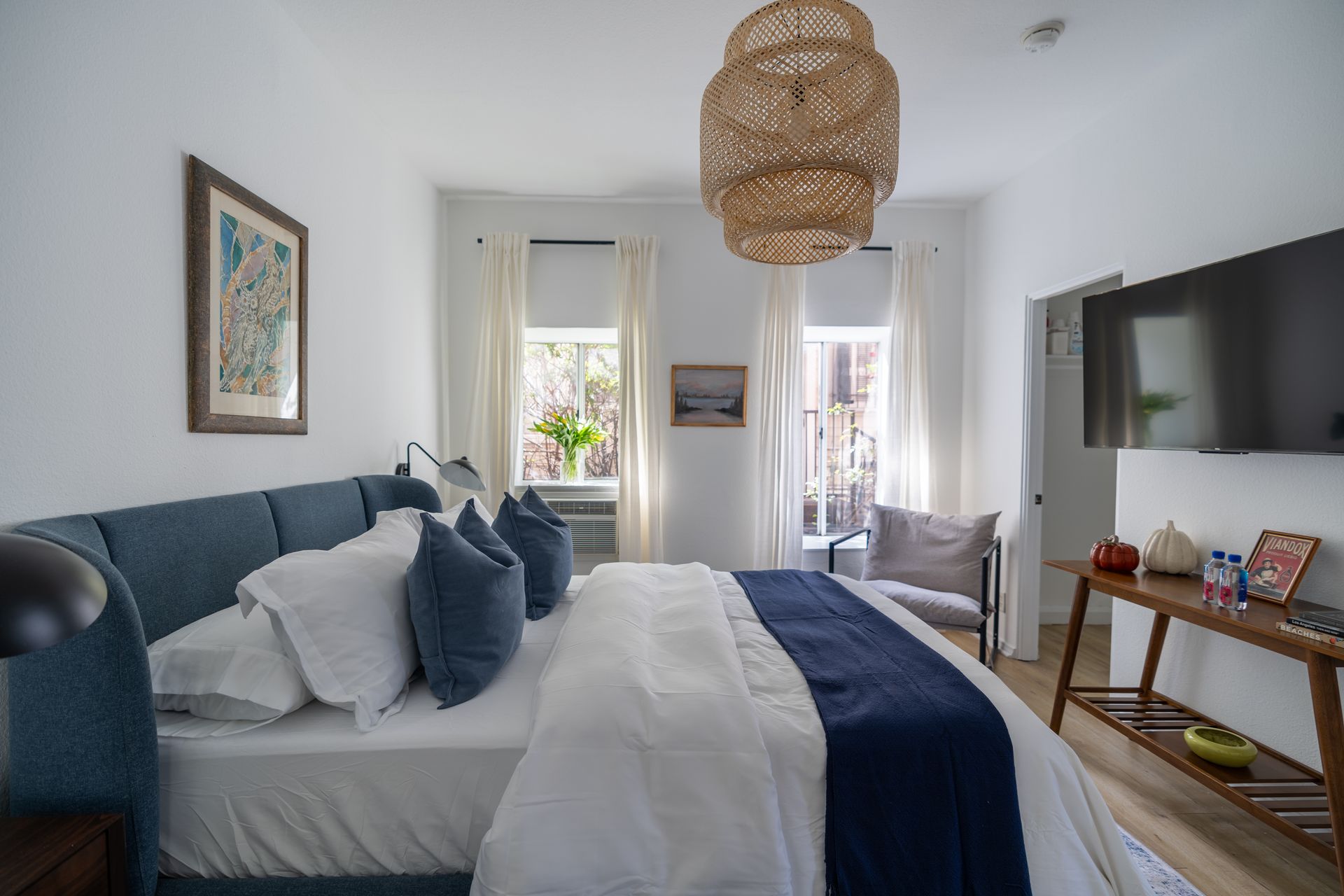 Bedroom with a blue bed, white bedding, and a large woven light fixture.