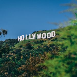 Hollywood sign on a grassy hillside under a blue sky.