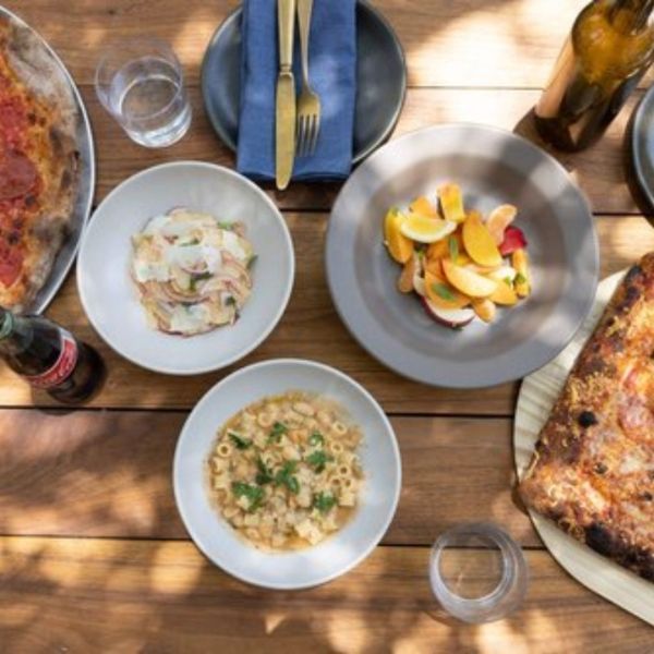 A table with pizza, pasta, salad, and cutlery set.