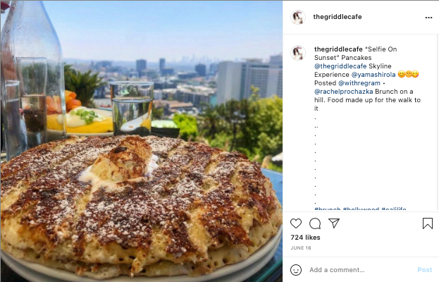 Pancakes with powdered sugar and butter, overlooking a city skyline.