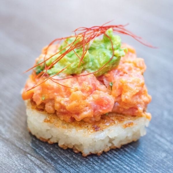 Sushi with diced salmon, avocado, and chili threads on a crispy rice cake.