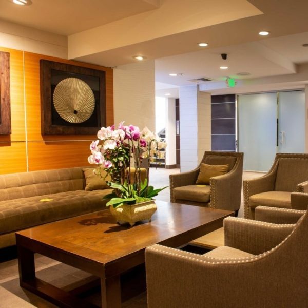 Cozy lobby with brown furniture, orchids, and artwork. Awaiting area with inviting ambiance.