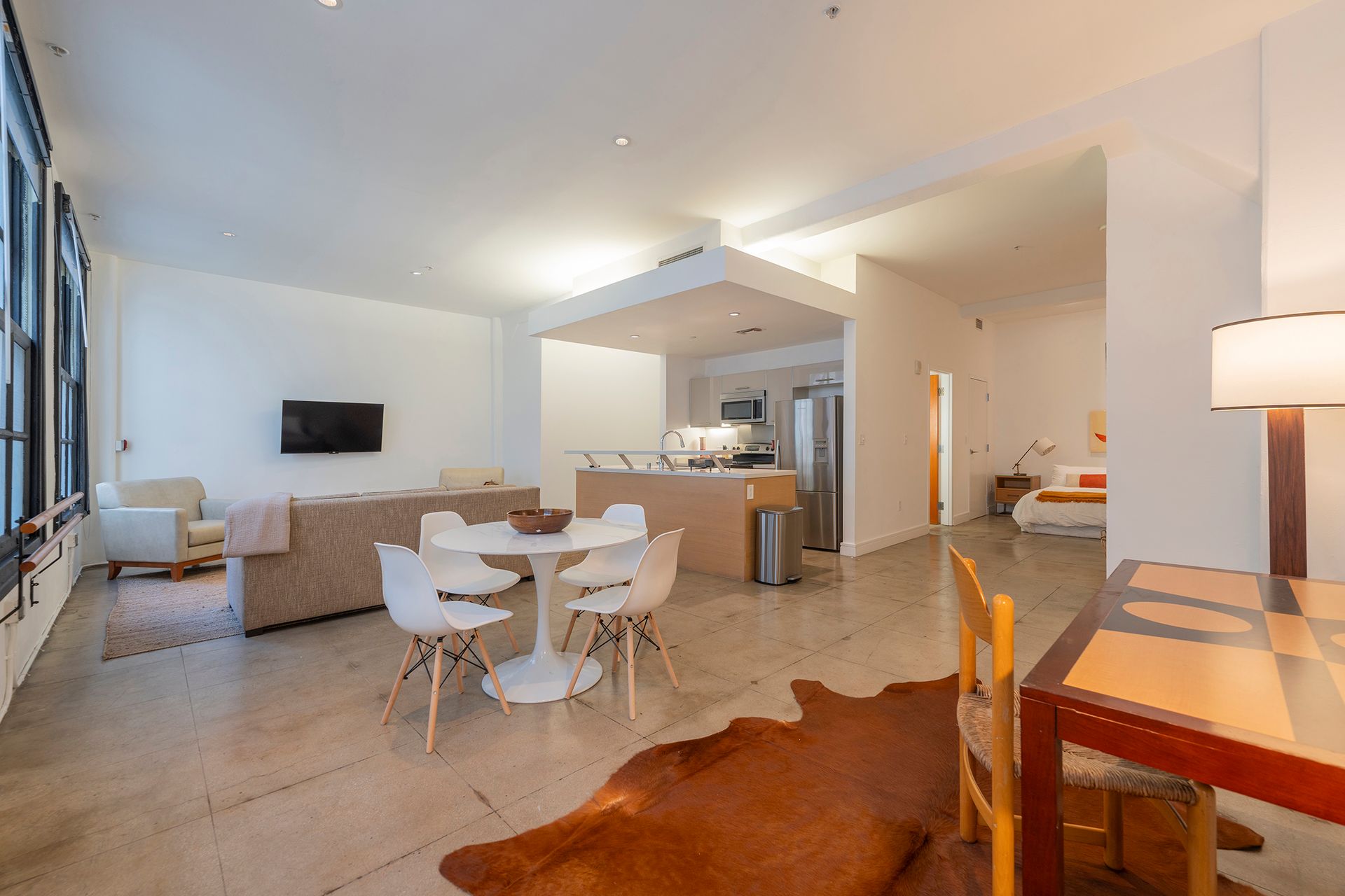 Open-concept living space with kitchen, dining area, and living room. Neutral colors, modern furniture, and a cowhide rug.