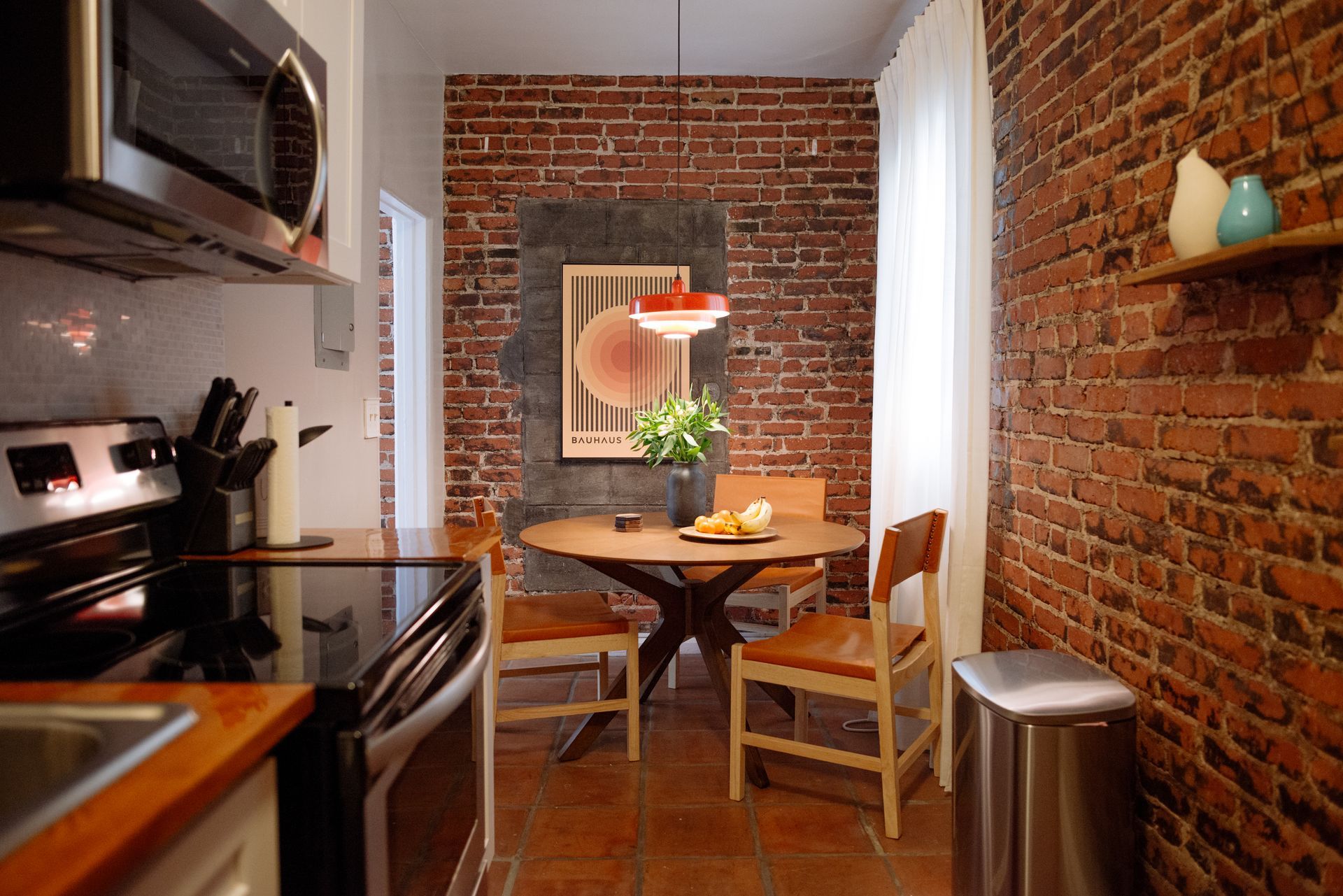 Small kitchen with exposed brick walls, a round dining table, and modern appliances.