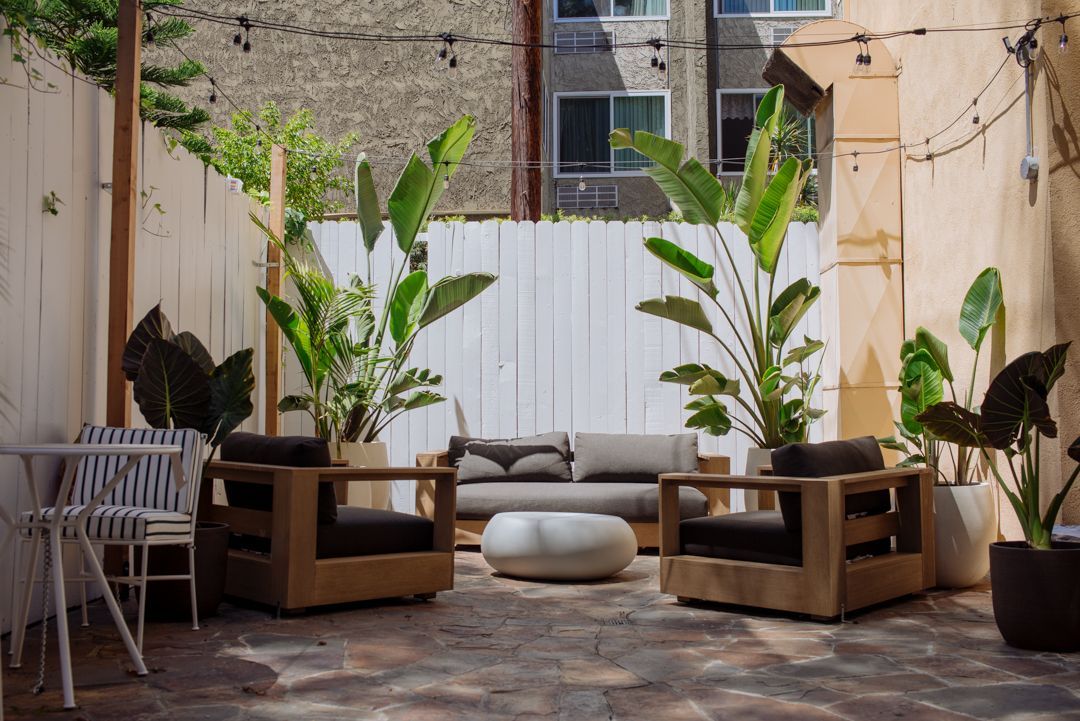 A patio with a couch , chairs , and plants.