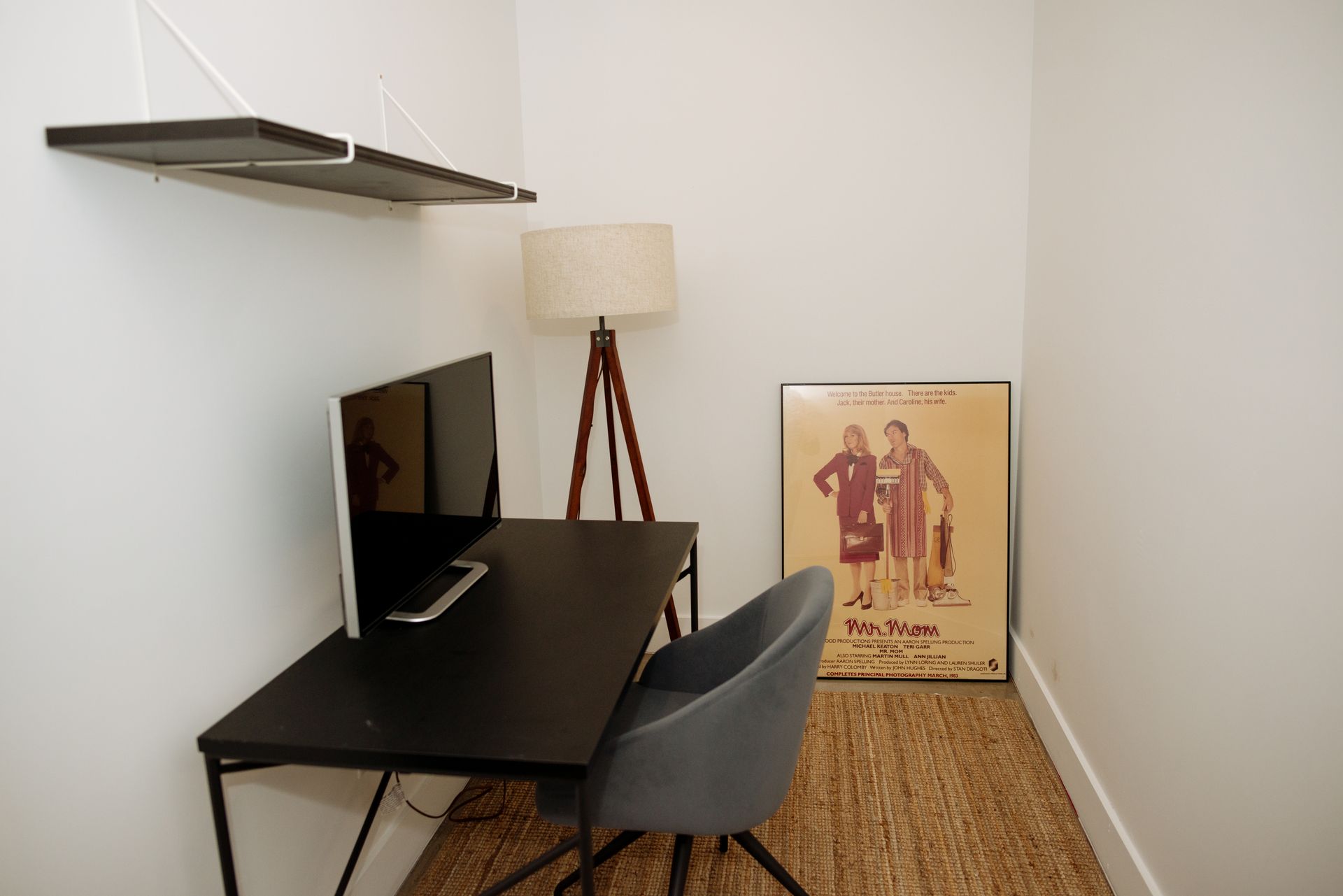 Small office nook with desk, computer, chair, lamp, and art print.