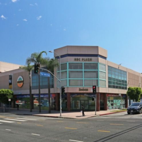 ABC Plaza building on a sunny day with shops and street traffic.