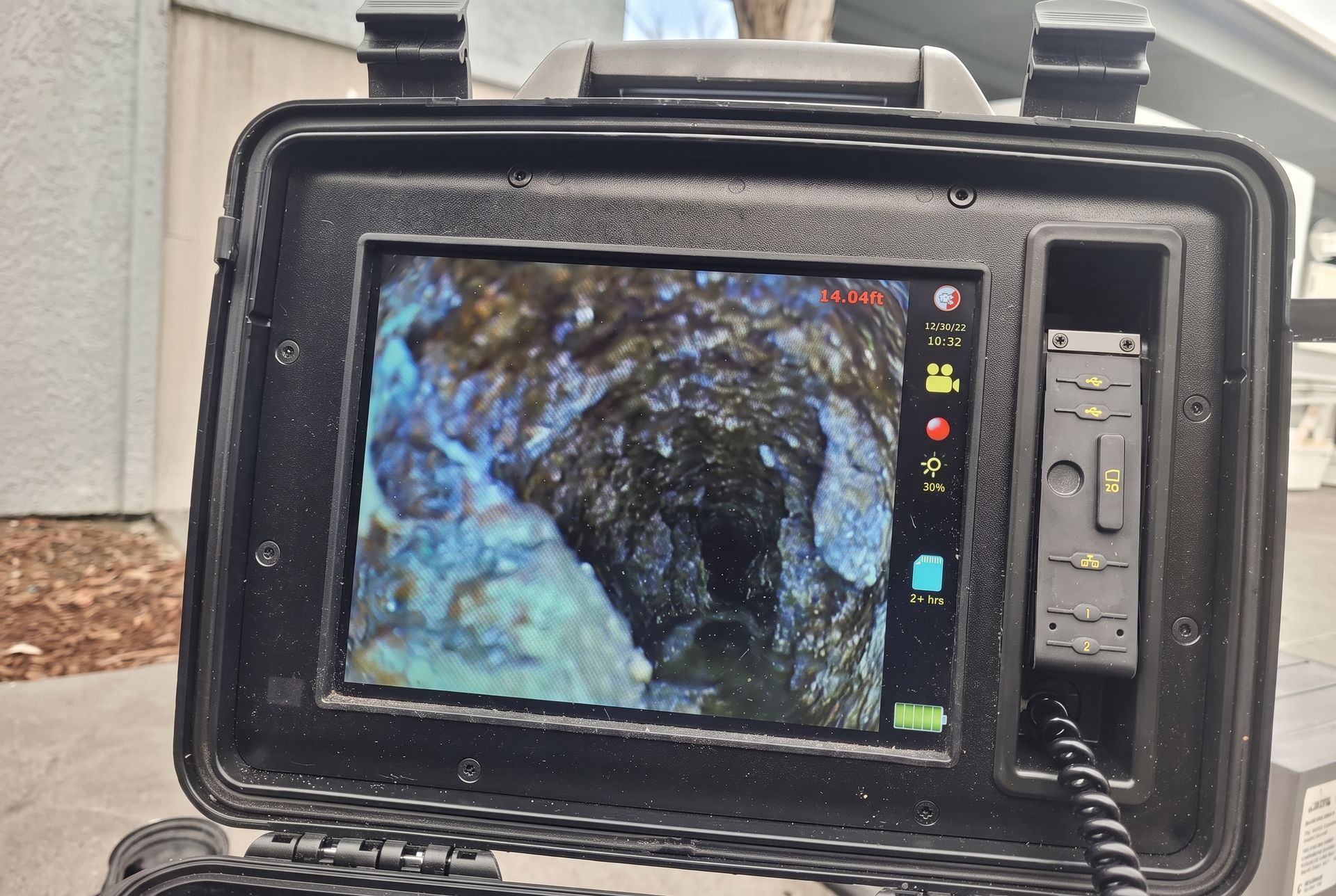 Inspection monitor showing a borescope view inside a rough, dark pipe or cavity
