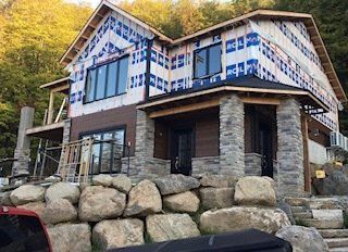 une grande maison est en construction à côté d une paroi rocheuse.