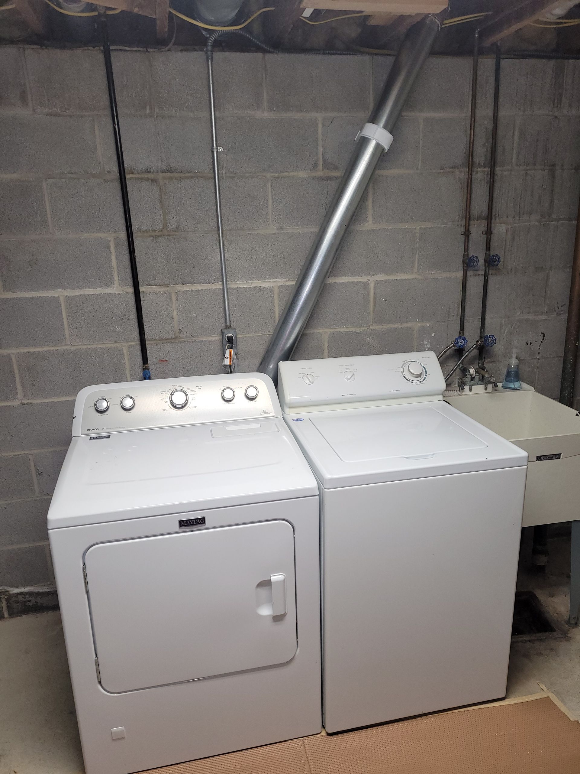 White dryer and washing machine in a basement laundry area.