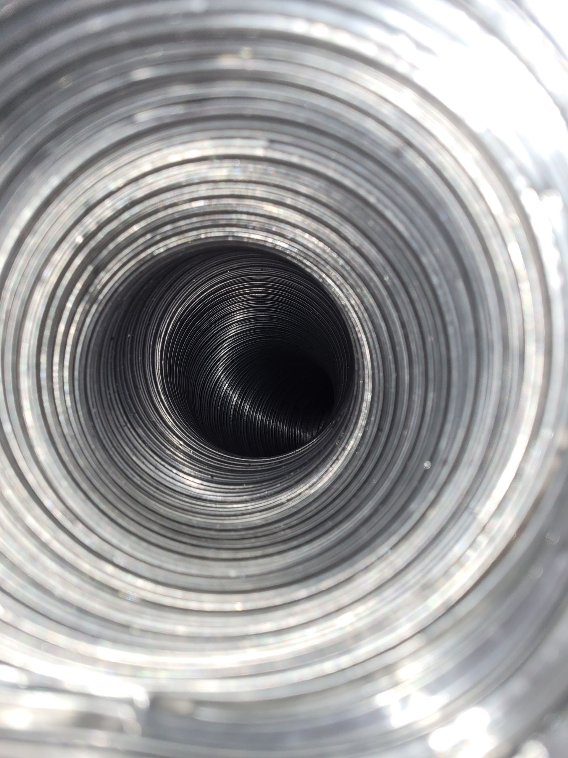 Inside view of a corrugated metal tube, leading to a dark, undefined space.