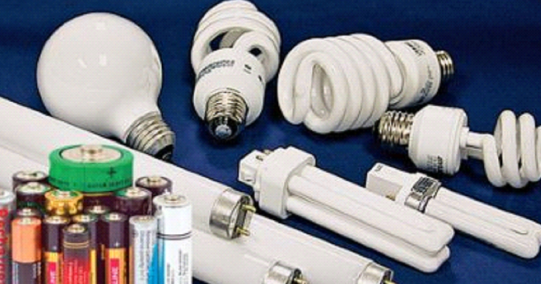 A bunch of different types of light bulbs and batteries on a table