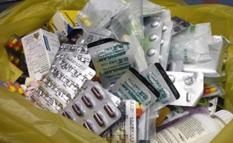 A yellow garbage bag filled with pills and boxes
